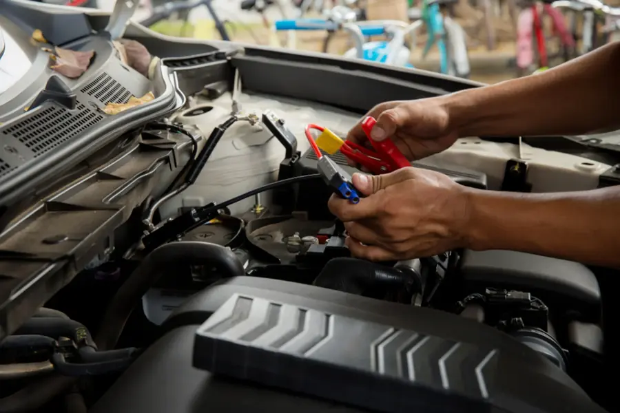 Close-up of hands working inside a vehicle's engine bay with a hand tool.