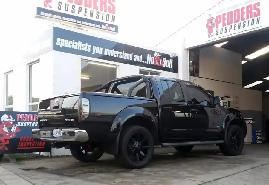 Black ute parked outside the Beecheys Service Centre workshop, operating under Pedders Suspension franchise signage.