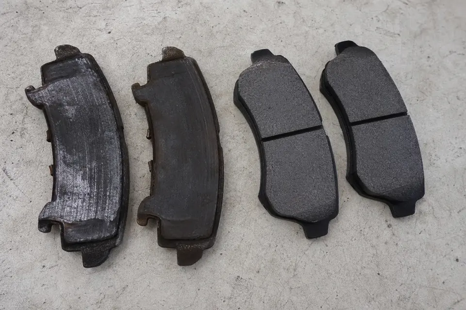 Worn and new brake pads arranged side by side