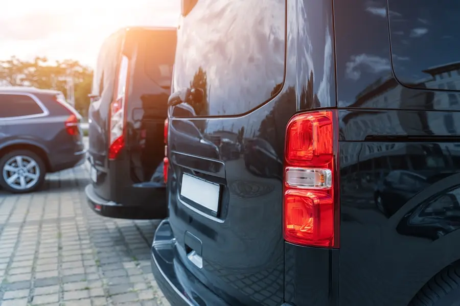 Close view of the rear of a dark commercial van parked at kerbside.