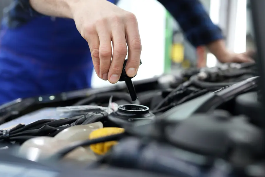 Mechanic checking an engine oil dipstick during a routine service.