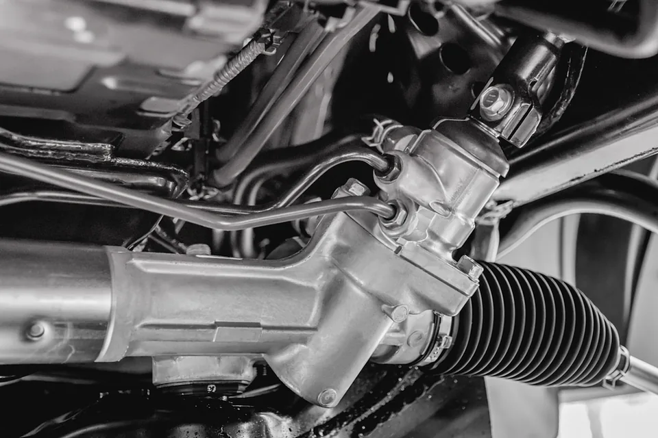 Close-up of a vehicle's power steering rack and linkage components exposed during a repair.