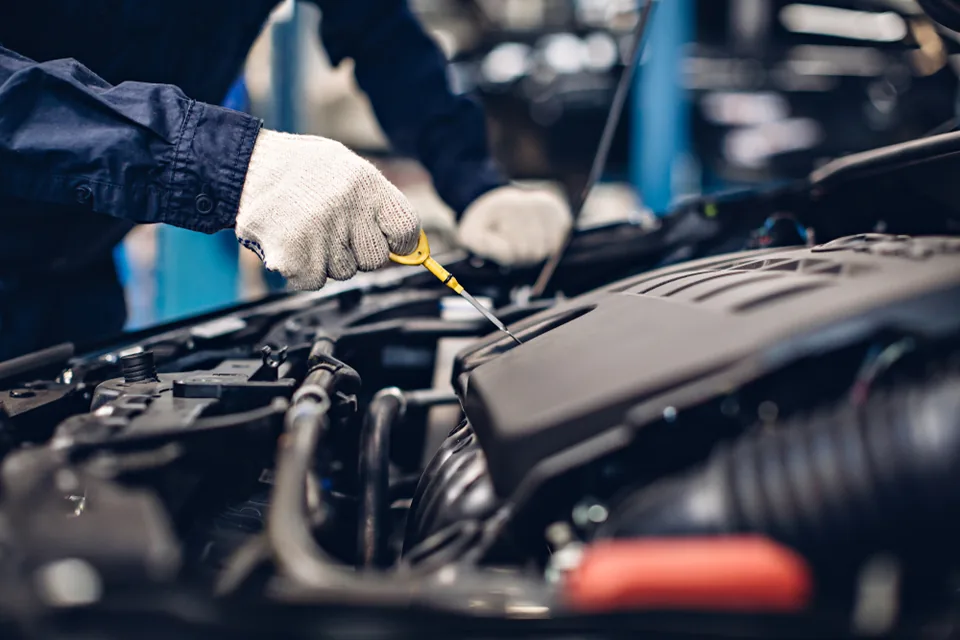 Mechanic's hand using a tool inside an open vehicle engine bay.