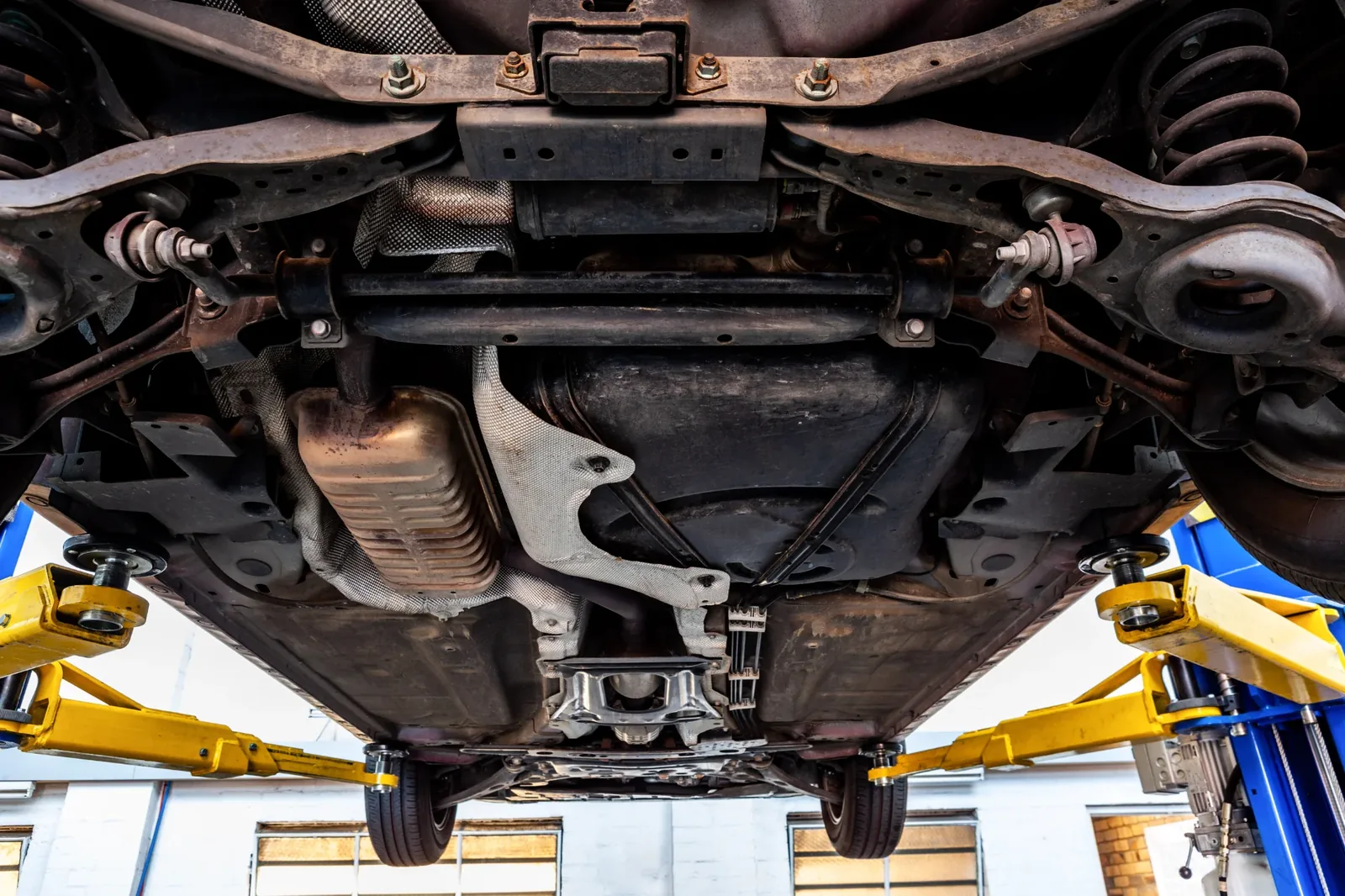 Wide view of a vehicle's underbody suspension components on a workshop hoist.
